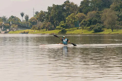 Simón Bolívar Park with a kayaker paddling on the lake. The man, wearing athletic clothing, moves his paddle.