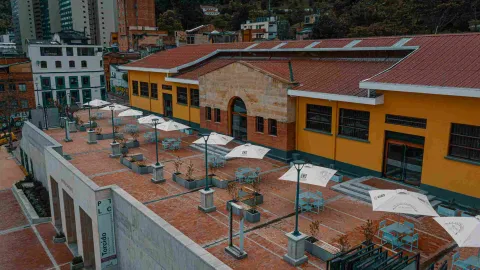 Plaza de Mercado La Concordia vista desde arriba, con varias mesas con parasoles. Al fondo se observan árboles y edificios.