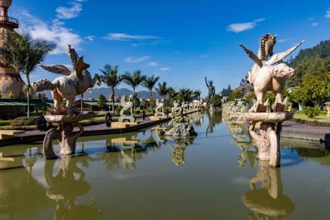 Un lago rodeado por estatuas de figuras mitológicas como minotauros y una medusa gigante.