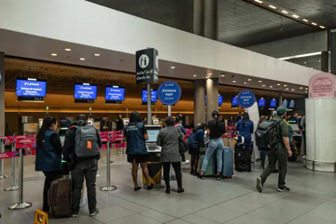 Interior of an airport showing some people walking with suitcases.