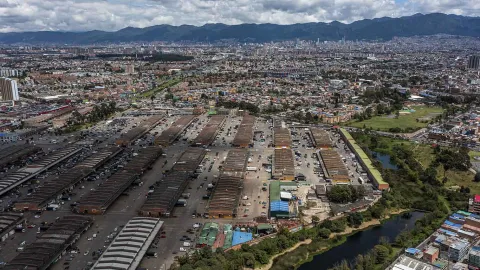 Desde arriba y de occidente a oriente se ve la plaza general con más de 10 gigantes bodegas y la ciudad de fondo. Hay un lago alrededor de la plaza.