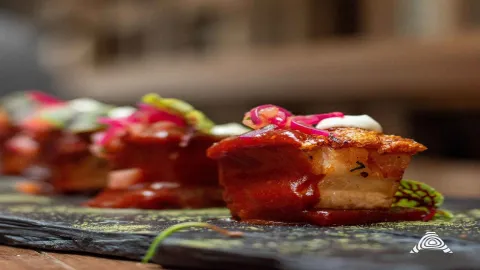 Suculentos trozos de carne con una costra crujiente, bañados en una rica salsa roja y adornados con cebolla encurtida.
