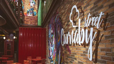 Pared de ladrillo con un vibrante mural de estilo graffiti y el letrero "Carnaby Street" iluminado.