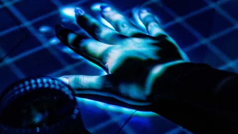 Una mano iluminada con proyecciones de luces azules y verdes, creando un efecto futurista.