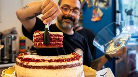Primer plano de hombre joven tomando un pedazo de una torta roja con blanca.