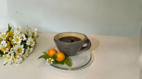 Taza de café decorada con uchuvas y un ramo de flores a un lado.