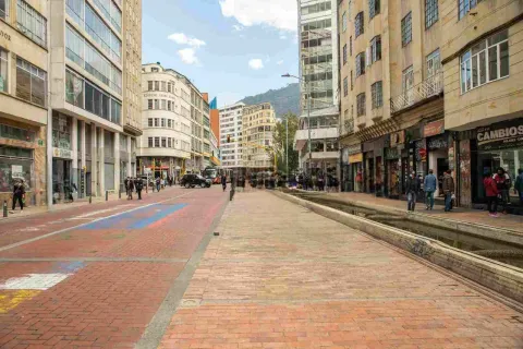 Alameda con una larga fuente de agua y varios edificios con locales comerciales alrededor.