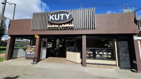 Fachada de local comercial en ladrillo y madera donde sobresale un aviso con una leyenda que dice: "Kuty".