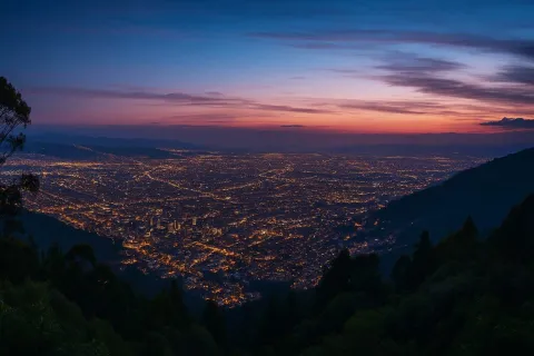  La ciudad iluminada al atardecer desde los cerros orientales. El cielo es rojo y violeta.
