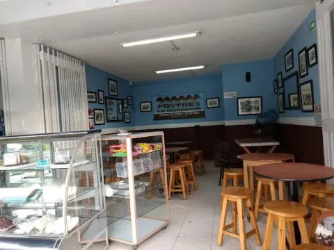 Interior de local comercial donde hay varias vitrinas, mesas y sillas.