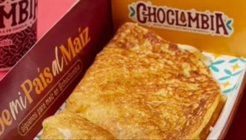  Primer plano de un trozo de pan dorado en una canasta con una leyenda que dice: "Choclombia".
