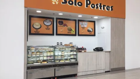 Pequeño colal comercial en un pasaje donde sobresale un aviso con una leyenda que dice: "Solo Postres". Hay dos vitrinas con postres y tres pantallas con información comercial.