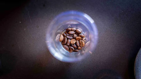Primer plano de copa de cristal con unos granos de café al interior.
