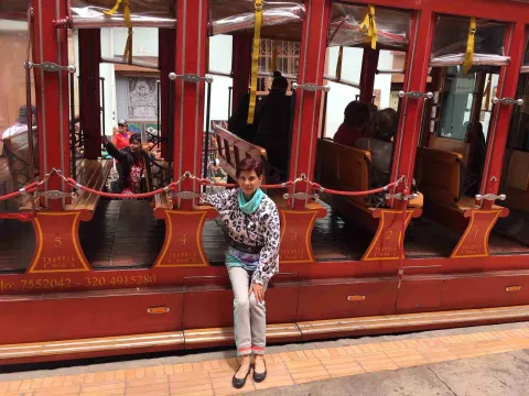  Mujer adulta sentada al frente de un tranvía de color rojo.