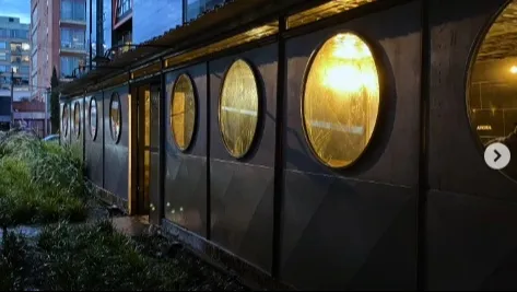  Pequeña edificación metálica y negra cuyas ventanas son circulares.