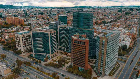  Panorámica de ciudad moderna vista desde arriba en la que hay altos edificios con fachadas con vidrios.