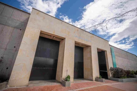 Fachada de edificación en piedra en la que destacan dos puertas altas y negras, parece que de metal, y una leyenda sobre la parte superior que dice: “GALERÍA SANTA FE”. 