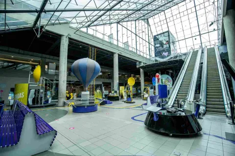 Gran salón donde se observa un globo, unas escaleras eléctricas y un gran techo en vidrio.