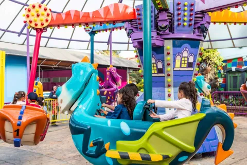 Un par de niños en una atracción mecánica en movimiento.