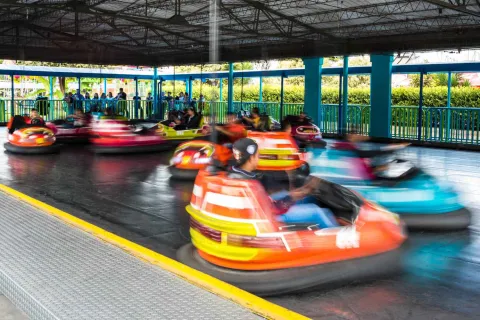 Personas en atracción mecánica de carros chocones en movimiento.