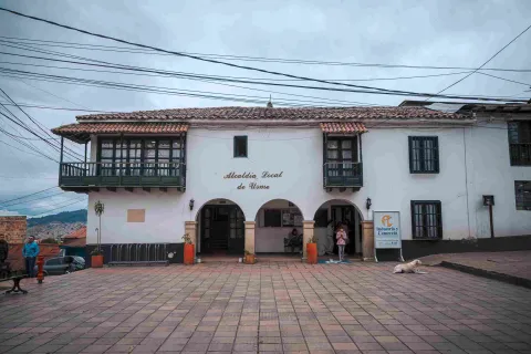 Facade of a two-story old white house, featuring a sign that reads: “Alcaldía Local de Usme.”