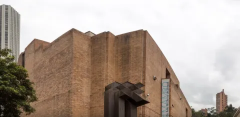 Facade of a large brick building with a prominent sign in blue letters that reads: “MAMBO”.