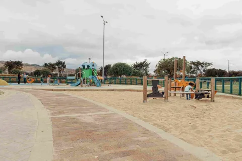 Parque infantil con arena en la que hay un niño jugando.