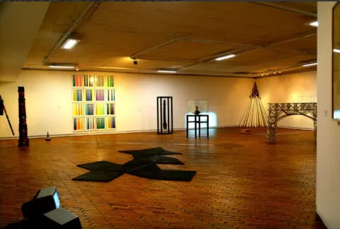 Interior room with picturesque works of art displayed on the walls and floor.