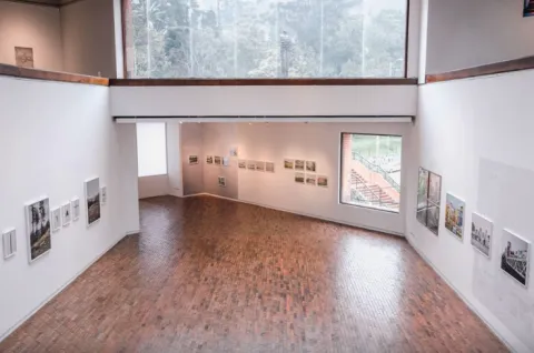 Well-lit, two-story interior room with a large window facing the street and several paintings on the white-painted walls.