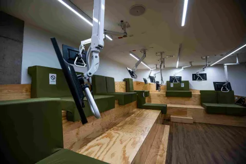A room featuring several television screens suspended from the ceiling and positioned in front of comfortable sofas.