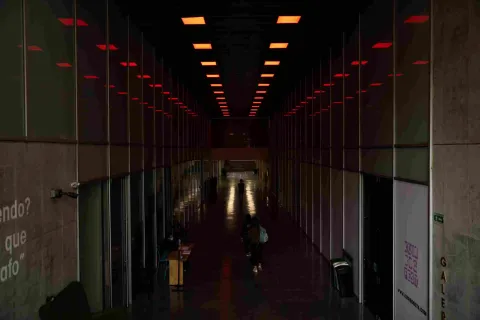 A long, dark interior hallway with offices on either side. A few people are walking around.