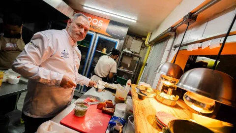 Un chef en su estación de trabajo, con ingredientes frescos y utensilios listos para la preparación de los platos. 