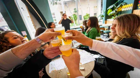 Un grupo de amigos brindando con vasos de cerveza en un ambiente relajado y alegre, celebrando juntos. 