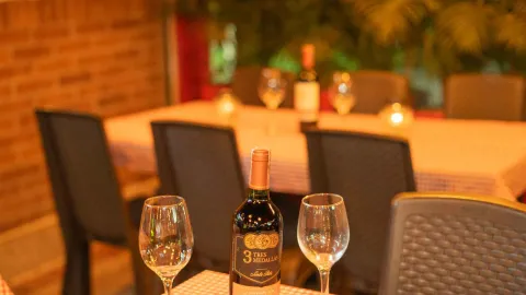 Una botella de vino "Tres Medallas" y dos copas vacías sobre una mesa, listas para ser servidas en un restaurante. 