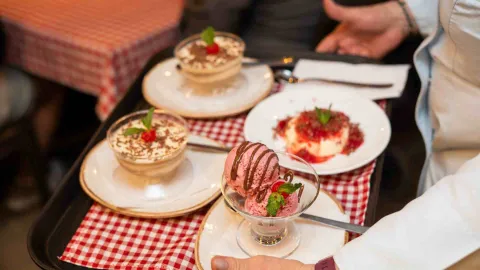 Un camarero presenta una bandeja con una variedad de postres italianos clásicos listos para servir.