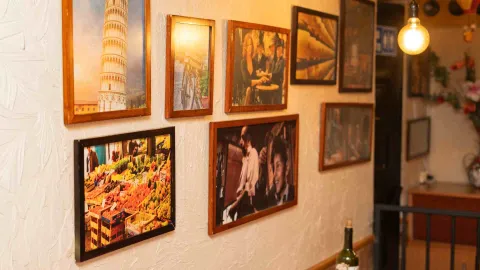  Pared decorada con una colección de fotografías enmarcadas que ilustran escenas y paisajes de Italia.