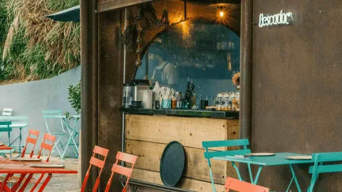 Barra de servicio exterior de madera rústica, con un espejo circular de fondo y un letrero de neón que dice Pescador.