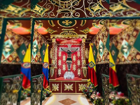 Figure of the so-called ""Lord of Miracles"" in a decorated space surrounded by the flags of Colombia and Bogotá.