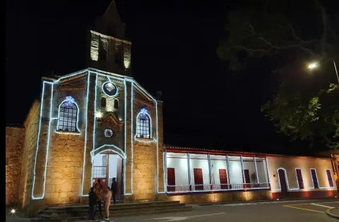 Panoramic view of the parish church's facade at night, adorned with neon lights.