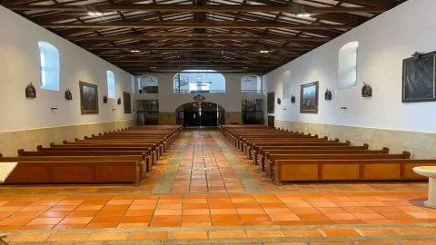 Interior view of the parish showing several rows of wooden pews, creating a serene atmosphere for visitors.