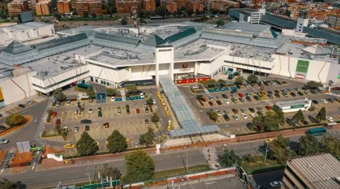 Plano general de lado de la fachada de una gran zona de edificaciones de mediana altura, con una amplia área de parqueaderos.