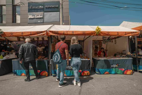 A young man and woman stand in front of a vendor stall, seemingly looking at handicrafts.