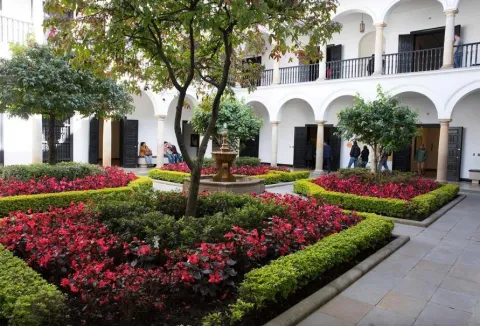 The Botero Museum's interior garden, completely adorned with red and green flowers on the ground. There's a fountain in the center.
