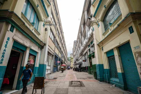 A young man wearing a face mask is walking along a street between old buildings.