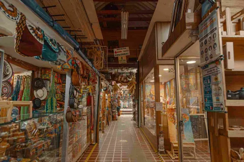 Interior de locales comerciales con coloridos artículos artesanales como sombreros, ruanas y hamacas.