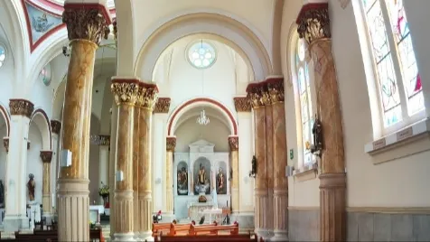 Parte interior de la parroquia en la que se ven varias columnas altas y paredes en forma de arcos.