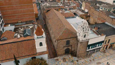 Vista desde arriba hacia abajo de la fachada y techo de la iglesia en tejas de ladrillo. Al lado hay otra iglesia.