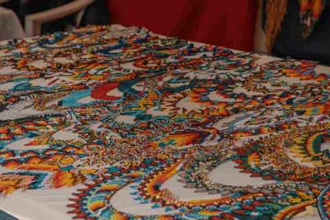 Close-up of a table displaying various handicrafts, such as necklaces and earrings, in the colors of the Colombian flag: yellow, blue, and red.