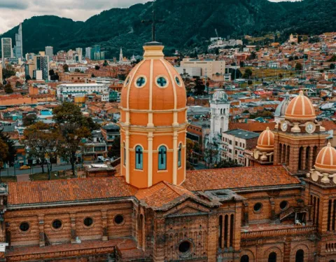 Primer plano de la torre de una iglesia vista desde arriba, de forma ovalada y de color naranja.