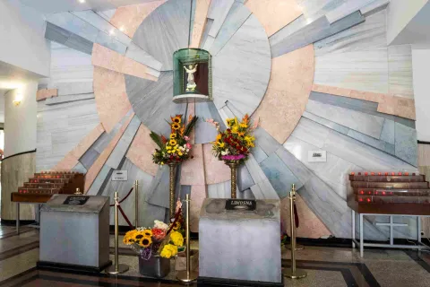 General view of the chapel interior, where the Divine Child is displayed in a glass case. Three floral arrangements surround it.